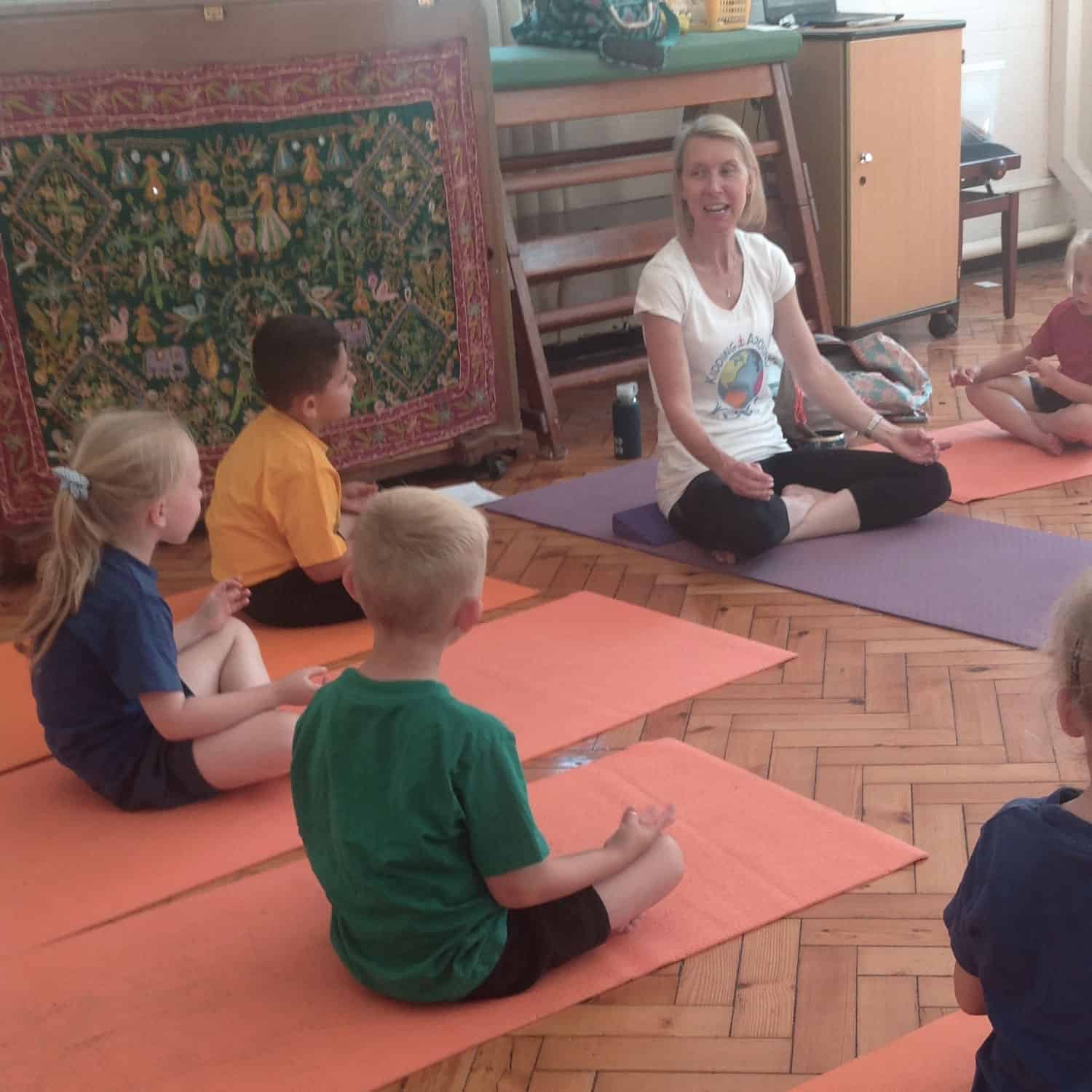 Group of children sat on mats learning yoga with teacher Emma Churchill in Kent